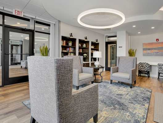 a resident clubhouse with gray chairs and a blue rug