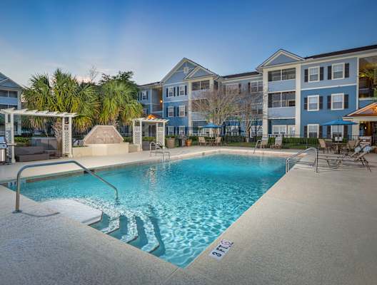 A swimming pool surrounded by a concrete floor and a white fence. at Magnolia Village Apartments, Jacksonville, FL, 32207