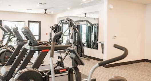 a gym with elliptical machines and a mirror