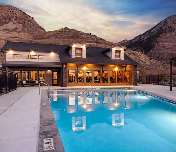 A large house with a pool in the foreground and mountains in the background.