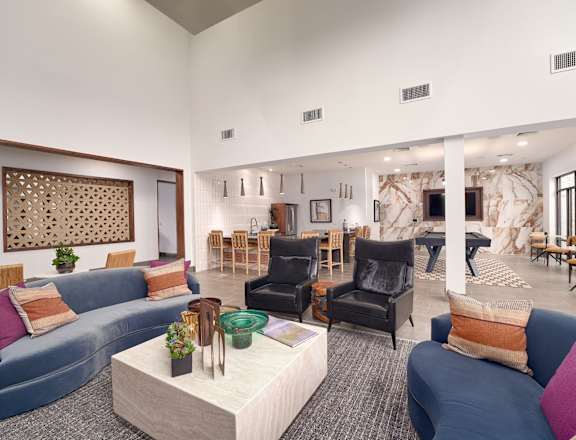 A living room with a blue couch, a white coffee table, and a wooden wall hanging.