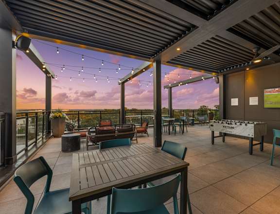 A patio with a table and chairs overlooking a sunset.