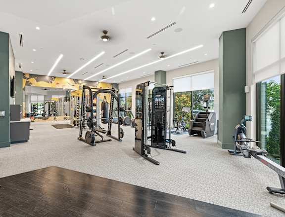 A gym with a variety of equipment including treadmills, weights, and exercise machines.