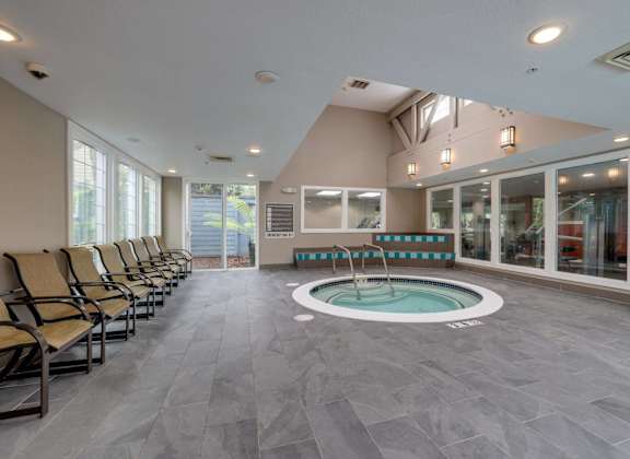 A spa room with a hot tub and lounge chairs.