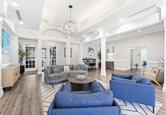 A spacious living room with a grey couch and blue chairs.
