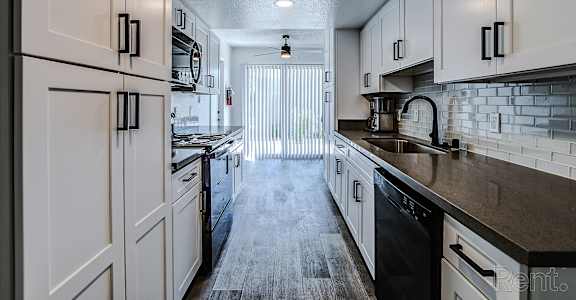 A kitchen with white cabinets and black appliances.