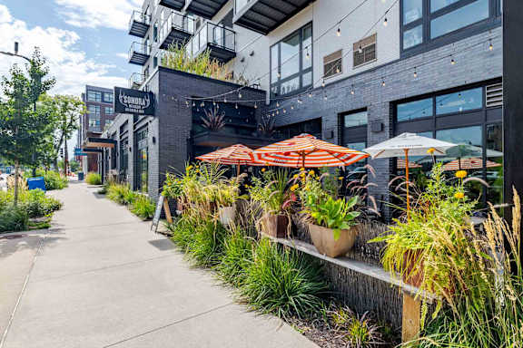 A patio area with tables and chairs and umbrellas.