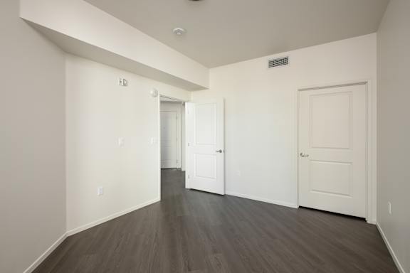 a bedroom with white walls and wood floors and a white door