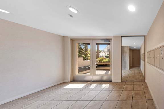A hallway with a tiled floor and a large mirror on the wall.
