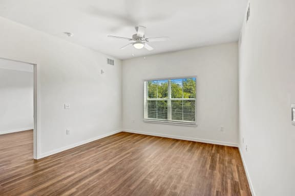 an empty living room with hardwood floors and a ceiling fan