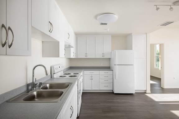 A white kitchen with a sink and a refrigerator.