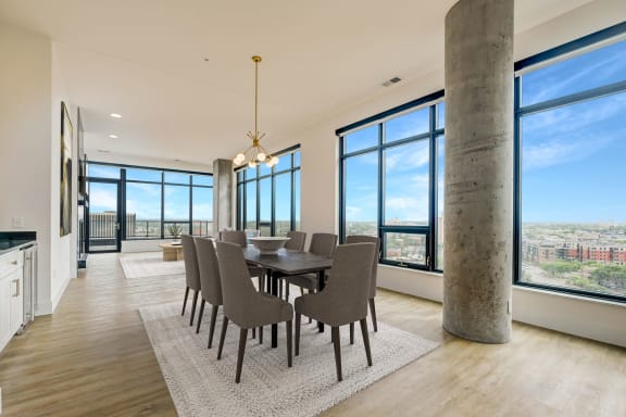 a dining area with a long wooden table and chairs and large windows with a view of the