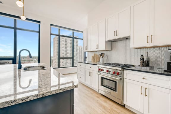 a kitchen with white cabinets and a large window