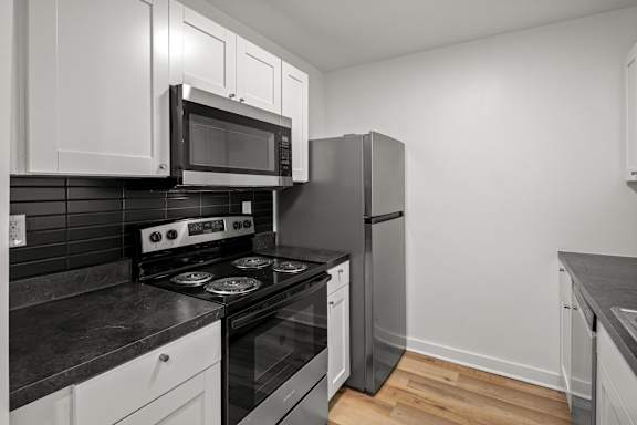 A kitchen with black countertops and white cabinets.
