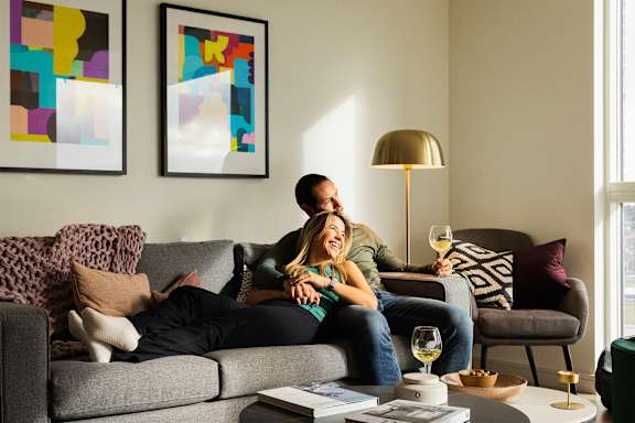 A woman is sitting on a couch with a glass of wine in her hand.