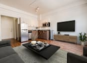 Thumbnail 1 of 8 - A modern living room with a grey couch and a black coffee table.