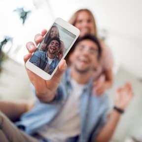a man holding up a cell phone with his family on it