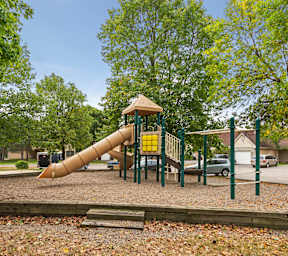 A playground with a yellow slide and a brown roof.