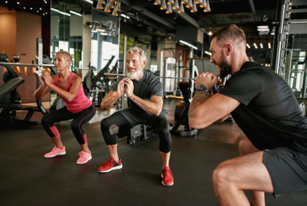 three people doing squats in a gym