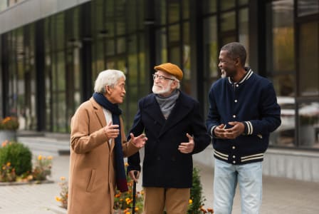 two men and a woman talking in front of a building