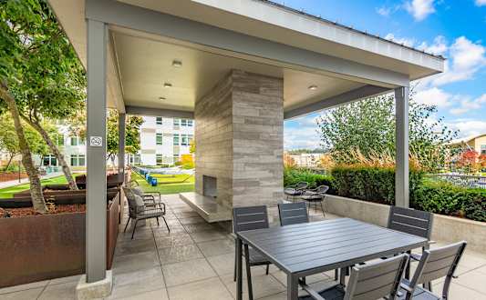 A patio with a table and chairs under a roof.