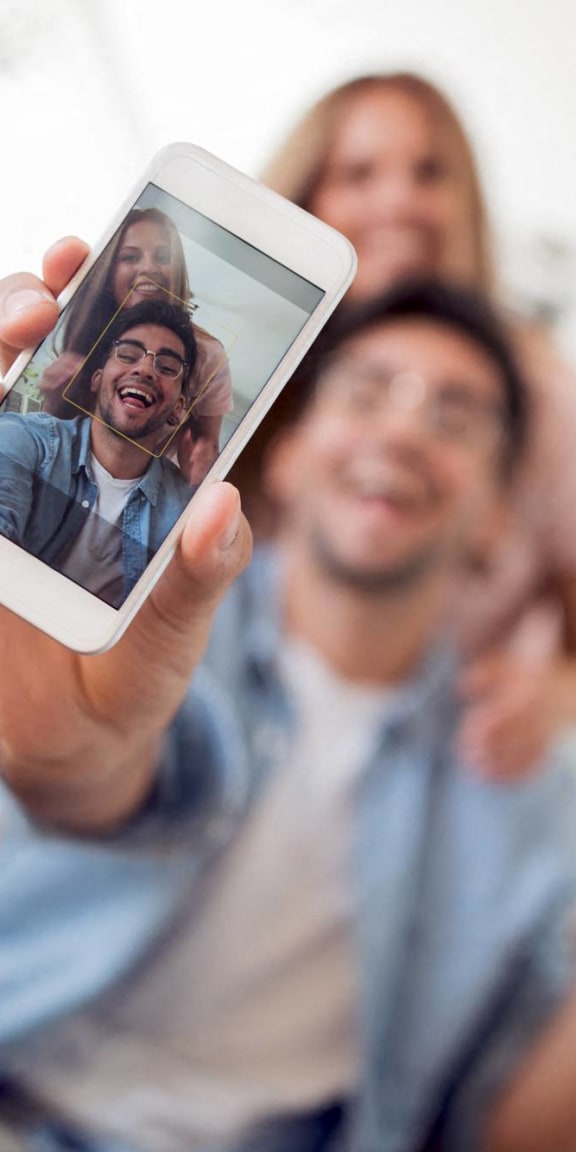 a man holding up a cell phone with his family on it