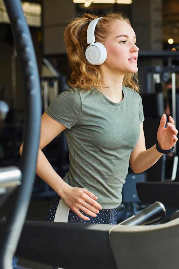 A woman is running on a treadmill in a gym.