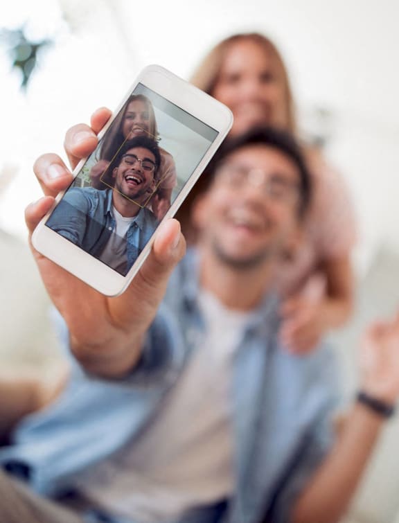 a man holding up a cell phone with his family on it