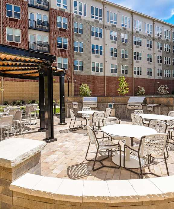 A patio with tables and chairs is surrounded by a brick wall.