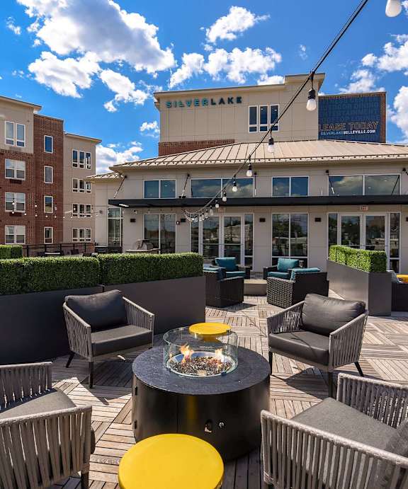 A patio with a fire pit and chairs.