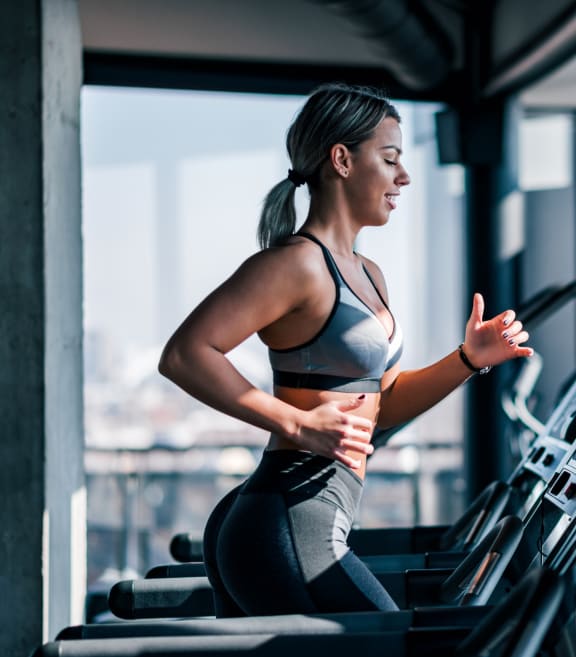 a woman running on a treadmill in a gym