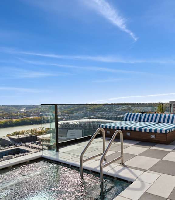 A rooftop pool area with blue and white striped sun loungers.