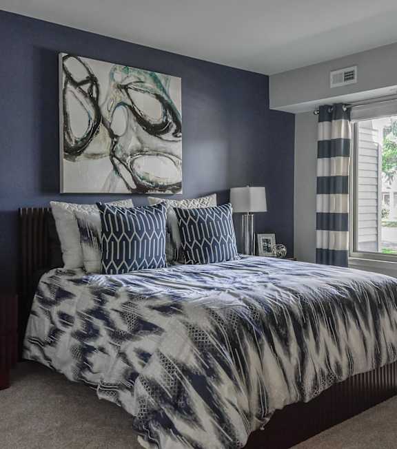 A bedroom with a large bed and a painting on the wall.