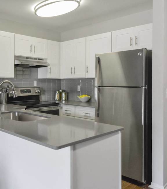 A modern kitchen with a stainless steel refrigerator and white cabinets.
