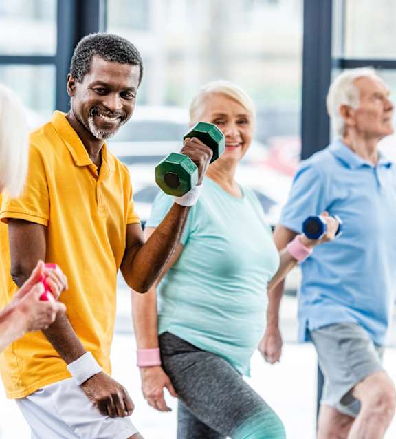 A group of people exercising with dumbbells in a gym.