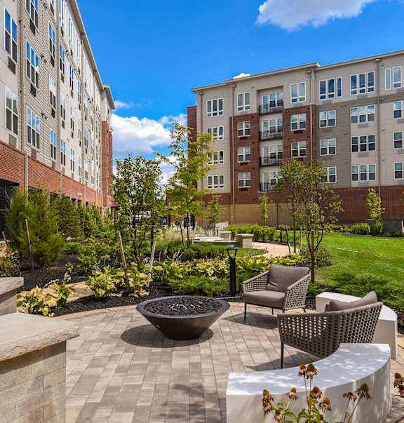 A courtyard with a fire pit and seating area surrounded by buildings.