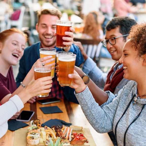 A group of people toasting with beer glasses at a table.