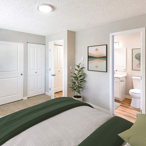 A bedroom with a bed in the foreground and a bathroom visible through the open door.