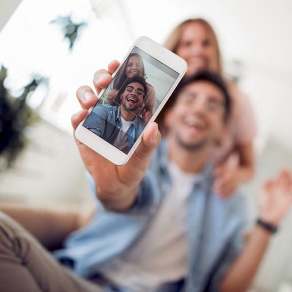a man holding up a cell phone with his family on it