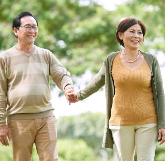 An older couple is standing outside a cafe, the man pointing to the right.