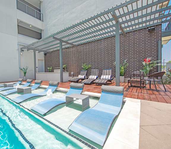 A pool with a slide and sun loungers.