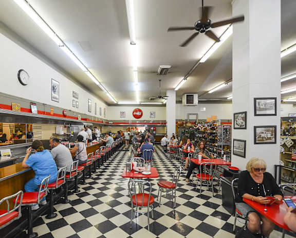 A restaurant with a black and white checkered floor and people sitting at tables.