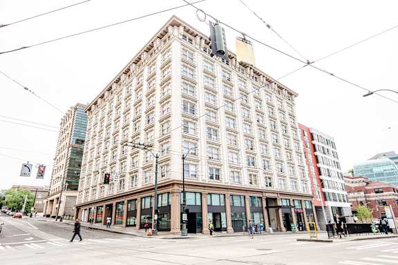 A large, old building with many windows sits in the middle of a city street.