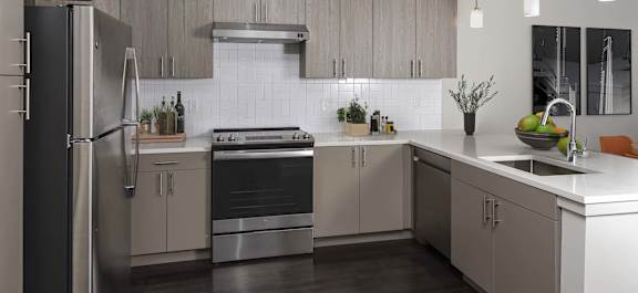A modern kitchen with a refrigerator, stove, and sink.