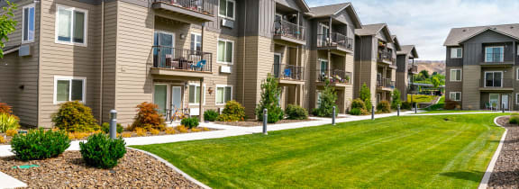 an exterior view of an apartment complex with a green lawn