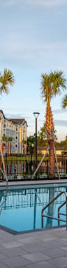 a swimming pool in front of a building with palm trees