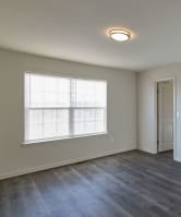an empty living room with wood floors and a window