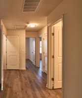 an empty hallway with wood floors and a white door