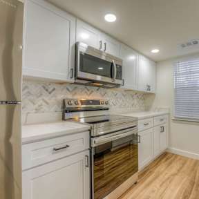A kitchen with white cabinets and wooden floors.at The Garden District Apartments, Germantown, TN 38138