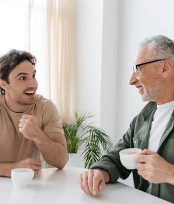 two men sitting at a table drinking coffee